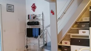 Ein Zimmer mit einem Bett, einem Schreibtisch, einem Stuhl, einem Bücherregal und einer Treppe.