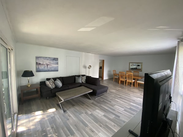 Ein modernes Wohnzimmer mit Sofa, Couchtisch und Essbereich.