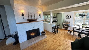 Eine moderne Küche mit weißem Kamin aus Ziegelsteinen, Holzboden und einem Essbereich mit Tisch und Stühlen.