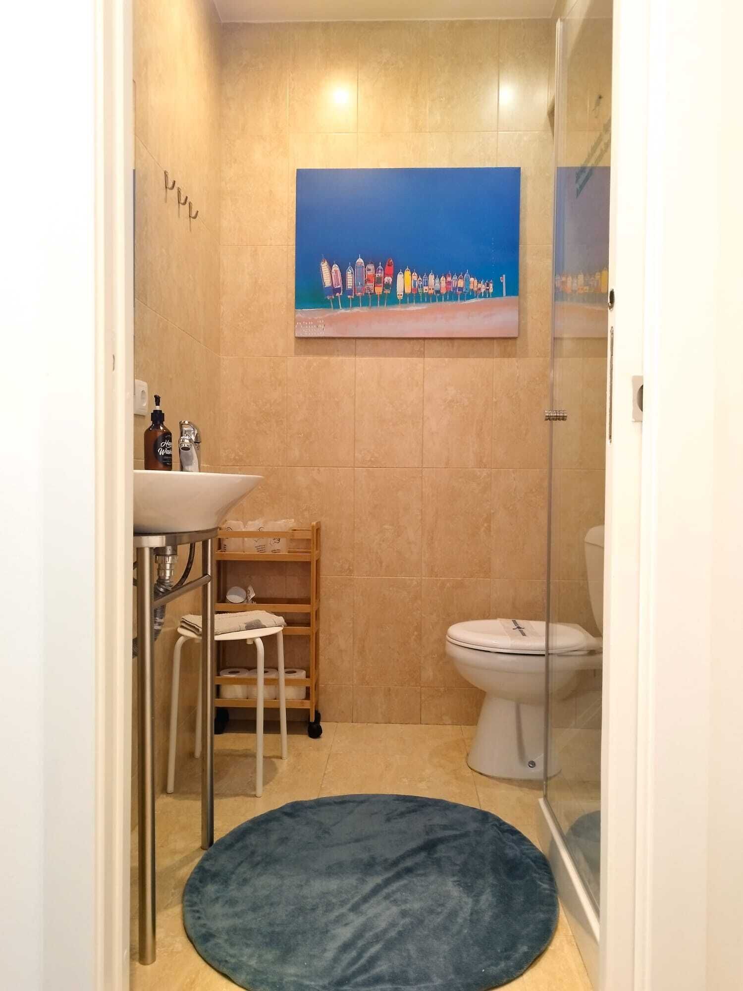 Et badeværelse med toilet, vask og brusebad.