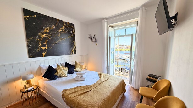 Habitación de hotel moderna con una cama, un cuadro abstracto grande, un televisor y vistas al exterior.