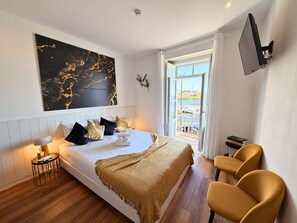 Habitación de hotel moderna con una cama, un cuadro abstracto grande, un televisor y vistas al exterior.