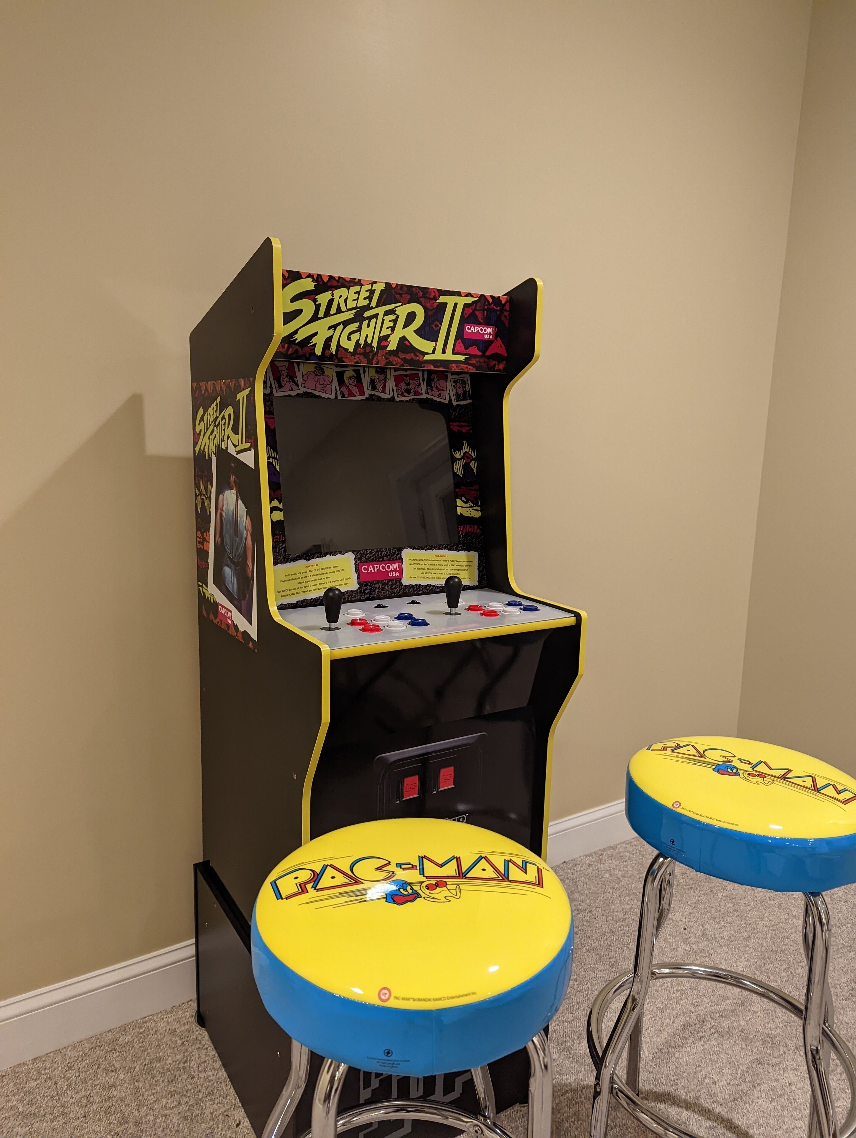 A retro arcade machine with two stools, featuring classic game characters.