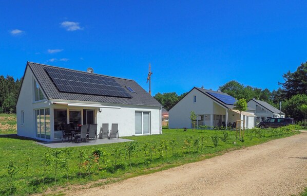 Two homes with solar panels and large windows offer comfortable living in a peaceful, natural setting.