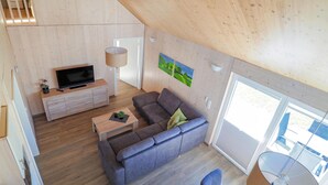 Un salon moderne avec un canapé, un téléviseur et des murs en bois.
