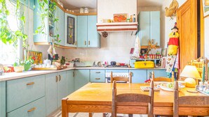 Una cocina con armarios color turquesa, una mesa de comedor de madera y varios utensilios de cocina.