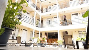 A multi-level atrium with balconies, potted plants, and outdoor seating. - La Maison 29 (Roseau)