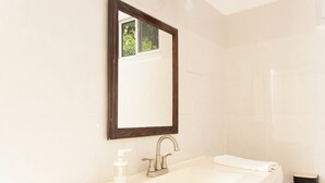 A bathroom with a white sink, a mirror, and a towel rack. - La Maison 29 (Roseau)
