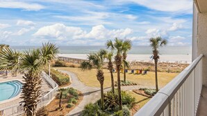 A balcony with a view of a beach, a swimming pool, and palm trees. - White Sands and Good Times (Orange Beach)