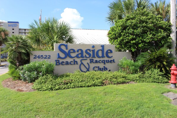 A sign for Seaside Beach & Racquet Club with a number 24522. - White Sands and Good Times (Orange Beach)