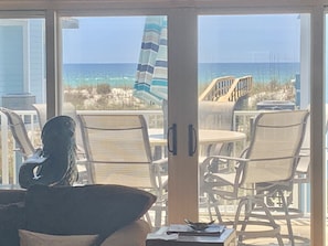 Enjoy the ocean view from the comfort of your seating area, featuring a large window and wicker chairs.