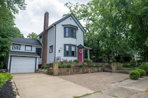 A two-story house with a garage, a brick chimney, and a front porch with a red door.