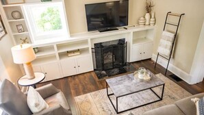 Una sala de estar con chimenea, televisor y una mesa de centro.