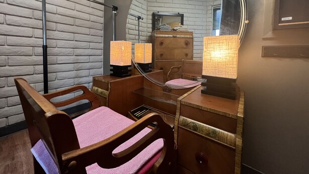 Un baño pequeño con tocador de madera, un espejo grande y una mesita.