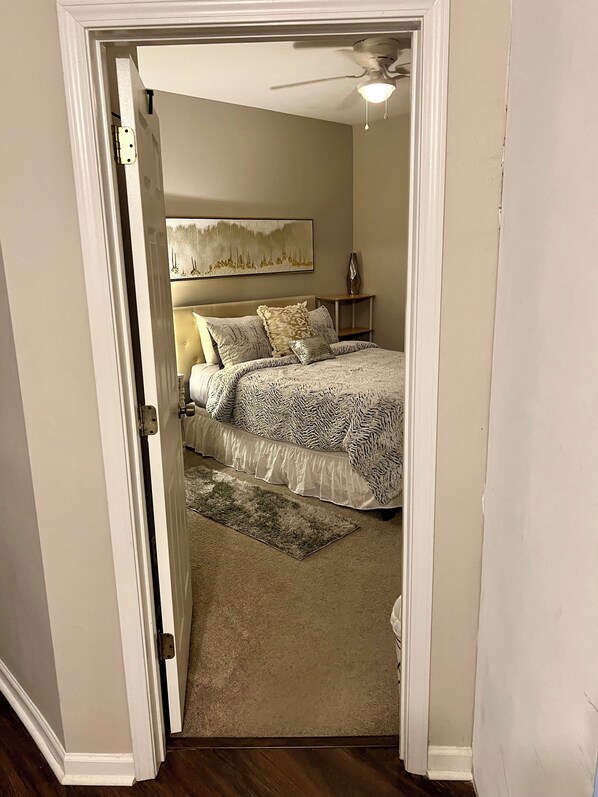 Une chambre à coucher avec un lit, un ventilateur de plafond, une table de chevet, une lampe et un tableau au mur.