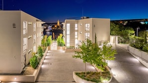 Een modern gebouwcomplex met een centrale binnenplaats, omgeven door bomen en verlicht met kunstmatige verlichting.