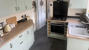 Una cocina compacta con estufa, horno, lavamanos y encimera de madera.