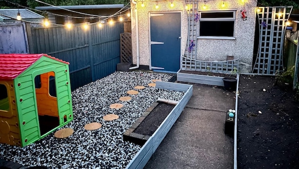 Patio con casita de juegos, un cobertizo pequeño y un jardín con piedras de adorno.