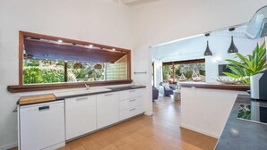 Moderni keittiö, jossa on suuri ikkuna, valkoiset kaapit ja puinen työtaso.