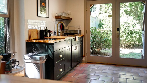 A kitchen with a tiled backsplash, a coffee machine, and a sink. - Private Cape Cod Cottage. Walk to Ellis Landing Beach! (Brewster)