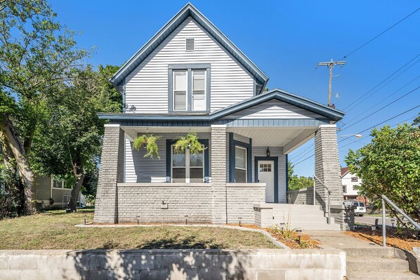 A two-story house with a gabled roof, a front porch, and a brick foundation. - Heritage Landing (Grand Rapids)