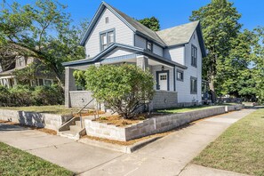 A two-story house with a front porch, a small tree in front, and a concrete sidewalk. - Heritage Landing (Grand Rapids)