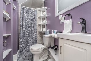 A bathroom with a toilet, a sink, a mirror, and a shower curtain. - Heritage Landing (Grand Rapids)