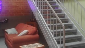 A staircase with metal railings, a red sofa, a small wooden table, and a ceiling fan.