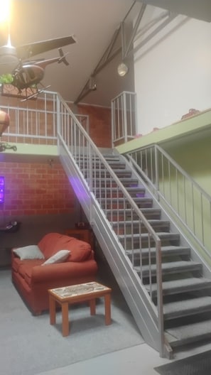 A staircase with metal railings, a red sofa, a small wooden table, and a ceiling fan.