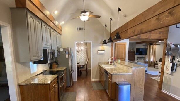 A spacious kitchen with wooden cabinets, granite countertops, a central island, and a ceiling fan. - Inviting farmhouse with private pool (Oxford)
