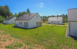 Houses with pitched roofs and flat facades stand amidst well-manicured lawns and small trees.