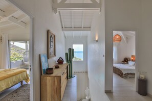 Een slaapkamer met een bed, een nachtkastje, een raam met uitzicht en een deur naar een andere kamer.