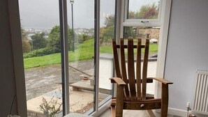 A room with a large window, a wooden chair, a small table, and a radiator. - FOINAVEN HOUSE, Quality 4 star self catering accommodation with panoramic views. (Ullapool)