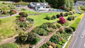 A house with a garden, a driveway, and a road with a speed limit sign. - FOINAVEN HOUSE, Quality 4 star self catering accommodation with panoramic views. (Ullapool)