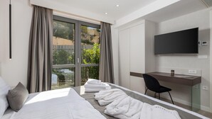 A modern hotel room with a large bed, a desk, a chair, and a TV. - 3 bedroom beach front apartment in Krk (Krk)
