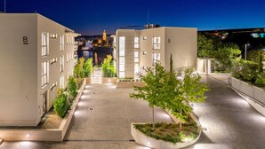 A modern building with a central courtyard featuring planters with trees and shrubs. - 3 bedroom beach front apartment in Krk (Krk)