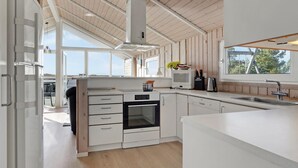 A modern kitchen with white cabinetry, a built-in oven, and a large window providing natural light. - Gorgeous home in Rømø with sauna (Rømø)