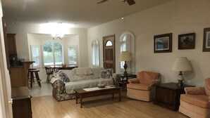 A living room with a sofa, armchairs, a coffee table, and a dining area with a table and chairs.