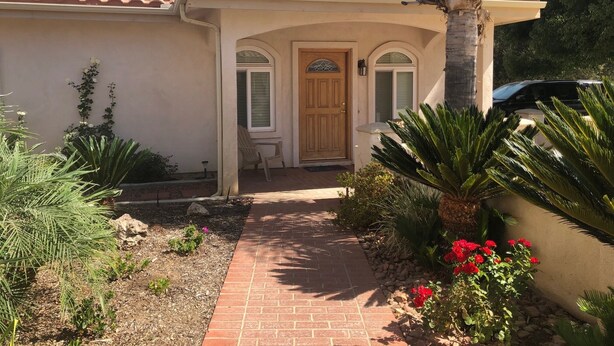 A house with a tiled roof, a front door, and a pathway leading to the entrance.