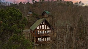 Een chalet met balkon, omringd door dicht bos en andere chalets.