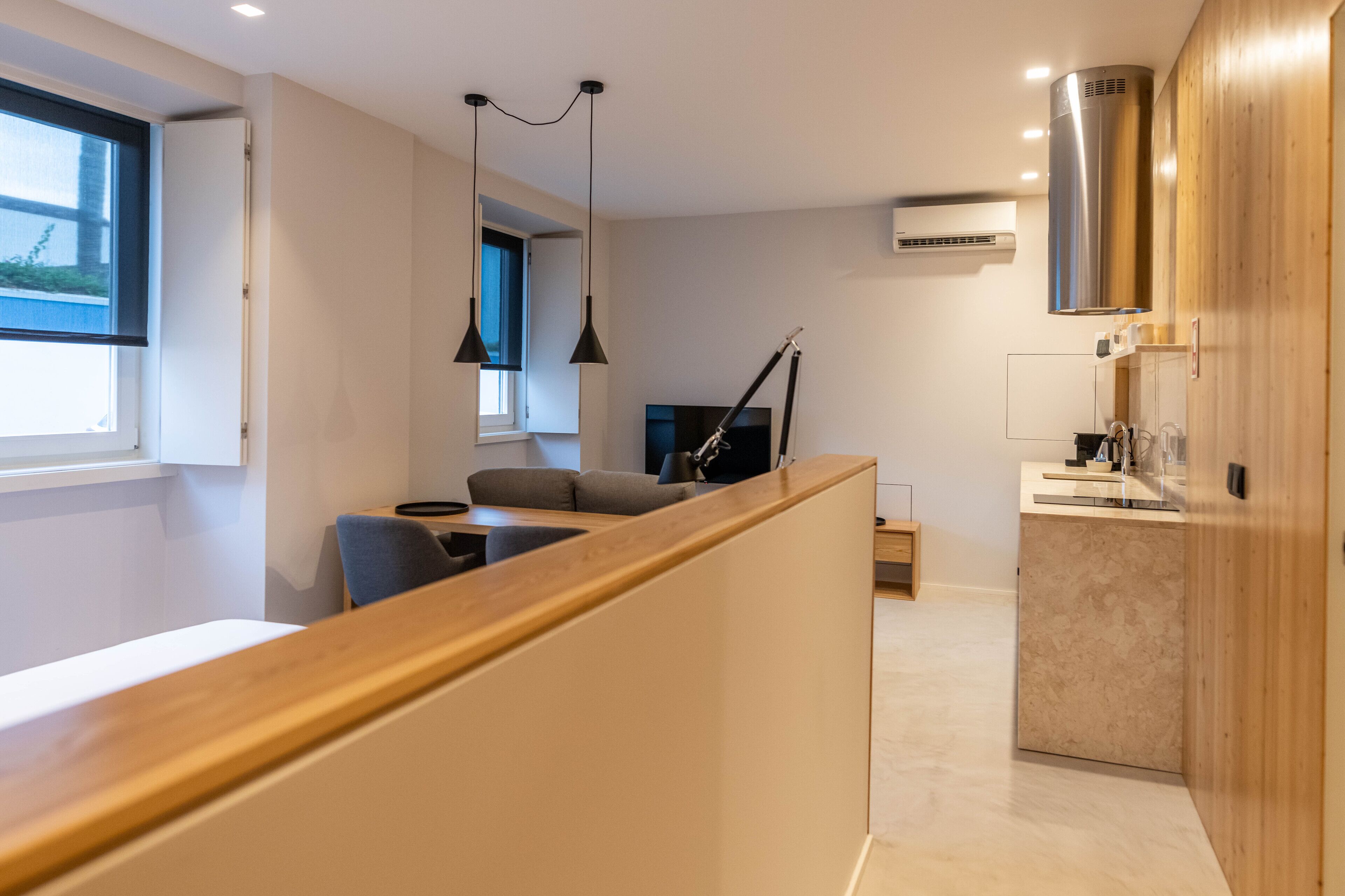 A modern kitchen with a wooden counter, a dining area with a sofa, and a TV.