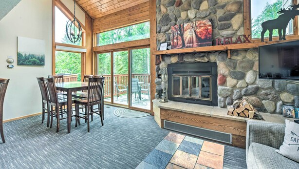 A cozy interior with a stone fireplace, wooden ceiling, and a dining area with chairs and a table. - Lutsen Mountains Retreat w/ Resort Amenities! (Lutsen)