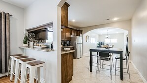 Une cuisine moderne dotée d’un îlot central, de tabourets de bar et d’un coin repas avec une table et des chaises.