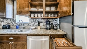 Une cuisine avec des meubles en bois, un réfrigérateur en acier inoxydable et un plan de travail en granit.