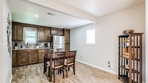 Une cuisine avec des meubles de rangement en bois, un réfrigérateur et une table à manger avec des chaises.