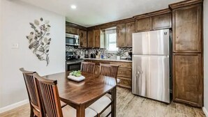 Une cuisine avec des meubles en bois, un réfrigérateur en acier inoxydable et une table à manger avec des chaises.