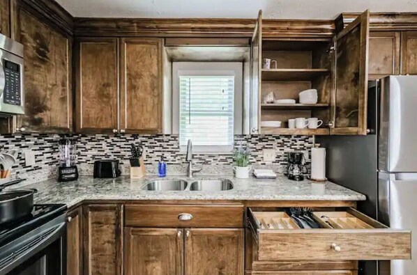Kitchen with double sink, stove, refrigerator, and ample counter space.