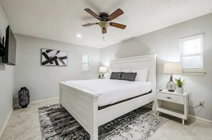 Relax in a serene bedroom with a comfortable bed, ceiling fan, and a stylish nightstand.