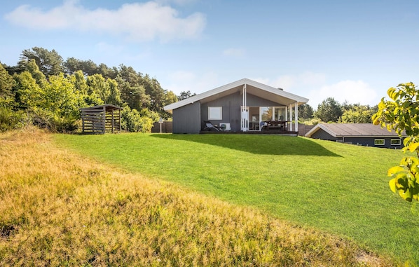 A modern house with a large lawn, a covered patio, and a garage.