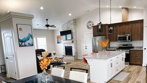 A modern kitchen with a central island, wooden cabinets, a microwave, and a stove. - 3 Peaks Mountain View Getaway w/Hot Tub! (Cedar City)